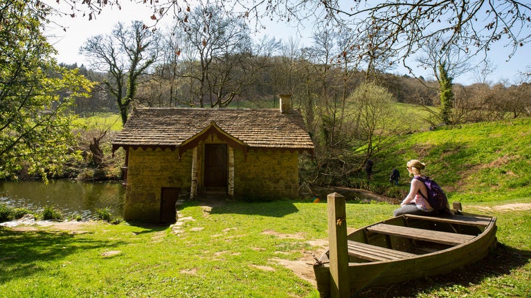 Visitor sat on a boat seat near the Boat House on Middle Pond at Woodchester Park, Gloucestershire